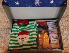 an open christmas gift box with pajamas and other items in it on carpeted floor