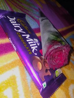 a wrapper with a pink flower sitting on top of it next to a bar of chocolate