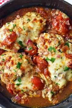 a skillet filled with meat covered in sauce and cheese on top of a checkered table cloth