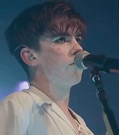 a woman with red hair and piercings on her face singing into a microphone at a concert