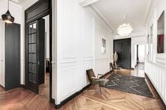 an empty room with white walls and wood floors, black doors and chandelier