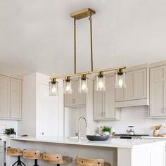 a kitchen island with stools and lights hanging from it's ceiling over the counter