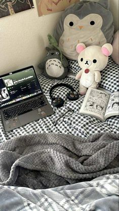 a laptop computer sitting on top of a bed next to a teddy bear and other items