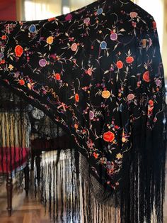 A magnificent Manton de Manila shawl made of black silk crepe fabric then heavily embroidered with colourful silk thread.  The embroidery is so well done you can barely tell which is the right side. The shawl is covered in embroidered flowers and leaves and around the edges are unusual depictions of musical symbols and bows. Quite a spectacular piece. In excellent condition  Measures 42" x 42" with a 20" woven fringe Black Embroidered Silk Shawl, Black Silk Bohemian Dupatta, Black Shawl With Intricate Embroidery In Traditional Drape, Traditional Black Floral Print Dupatta, Black Pashmina Shawl With Intricate Embroidery, Black Embroidered Pashmina Shawl, Black Silk Embroidered Fabric With Dupatta, Black Intricate Embroidery Pashmina Shawl, Embroidered Silk Shawl Scarf