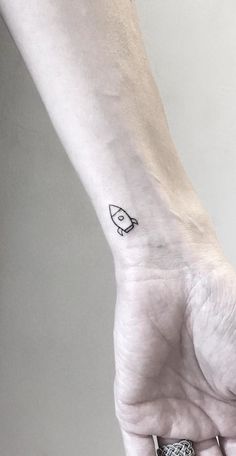 a small black and white rocket ship tattoo on the wrist