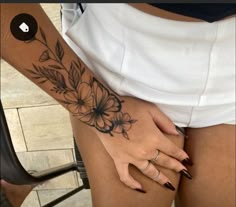 a woman's leg with flowers on it and her hand in the other side