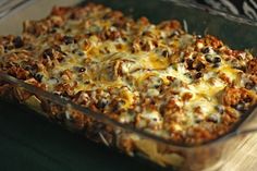 a casserole dish filled with meat, cheese and other toppings on a wooden table