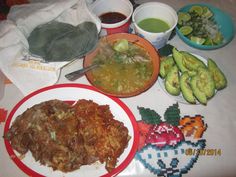 a table topped with plates of food next to bowls of sauce and avocados