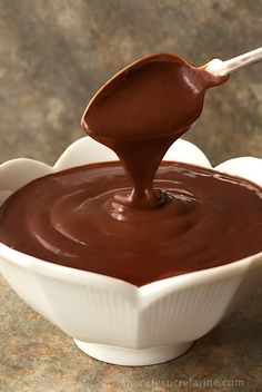 a spoon full of melted chocolate in a white bowl