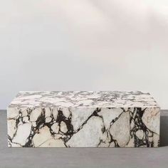 a marble bench sitting on top of a cement floor next to a white and black wall