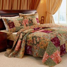 a bed covered in a colorful quilt and pillows