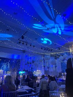 a room filled with tables and chairs covered in blue lights at an event or party