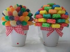 two white vases filled with candy and candies on top of a white table