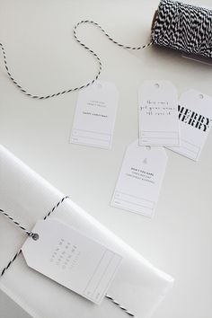 three tags are attached to a roll of twine on a white surface with black and white stripes