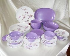 a table topped with purple dishes and plates