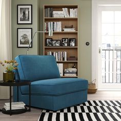 a living room with a gray chair and bookshelf in the corner, next to a black and white striped rug