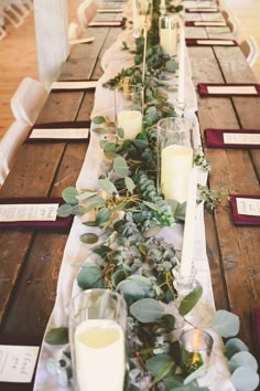 a long table with candles and greenery on it