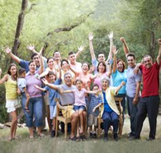 a group of people standing and sitting in the grass with their hands up to the sky