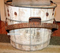 an old wooden bucket sitting on top of a counter next to a door with rusted metal handles