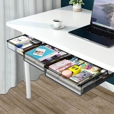 a laptop computer sitting on top of a white desk next to a drawer filled with magazines