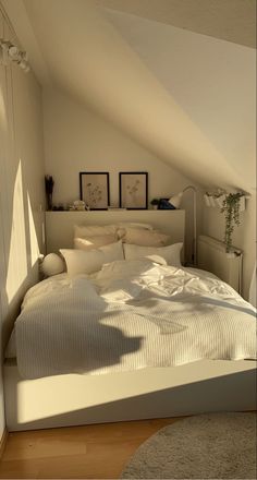 a white bed sitting in a bedroom next to a wall with pictures hanging on it