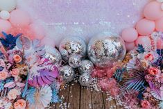 an assortment of balloons and flowers on a wooden floor with pastel pinks, silvers and blue