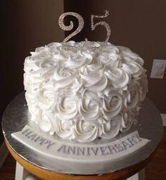 a 25th birthday cake with white frosting and roses on the top is decorated with silver numbers