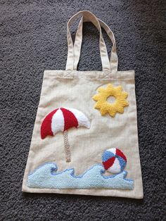 a tote bag with an umbrella and beach ball on the front sitting on carpet