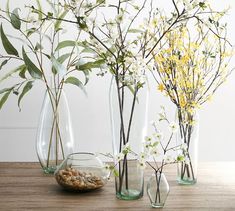 three vases filled with flowers and rocks on a wooden table next to each other