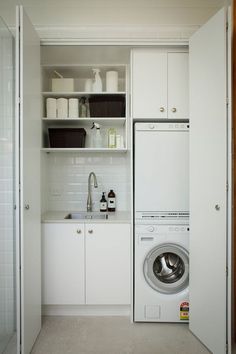 a washer and dryer in a small room with open shelves on the wall