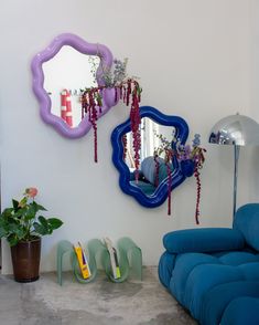 a living room with blue couches and mirrors on the wall, plants in vases