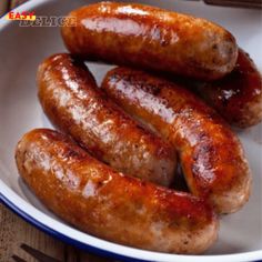 three sausages in a white bowl on a wooden table