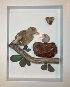 a white frame with some rocks and a bird on it's body in front of a tree branch