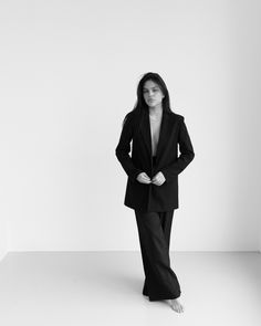 a woman in a black suit standing with her hands on her hips