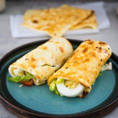 two burritos sitting on top of a green plate next to some pita bread