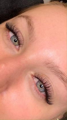 a close up of a woman's eyes with long lashes and blue eyeshadow