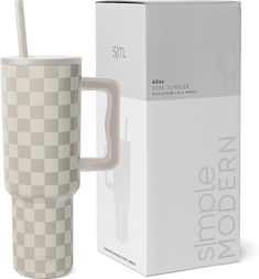 a white and grey checkered coffee mug with a straw in it next to a box