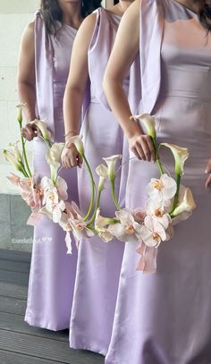 the bridesmaids are holding their bouquets with orchids in each one's hands