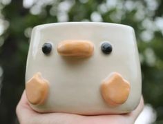 a hand holding a ceramic bird with two eyes