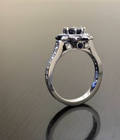 DeKara Designs Special Order Metal- 90% Platinum, 10% Iridium. Stones- Natural Round Ceylon Blue Sapphire 1.15 Carats, 34 Round Diamonds 0.62 Carats, 2 Round Blue Sapphires. Art Deco Inspired Platinum Diamond Sapphire Engagement Ring. The center fiery has eight prongs, which not only makes it extremely secure, but gives it a unique look. This ring is truly breath taking with 16 pave set diamonds surrounding the center sapphire. There are another seven pave set round diamonds on each side of the Silver Sapphire Princess Cut Platinum Ring, White Gold Sapphire Cluster Promise Ring, Platinum Sapphire Ring With Princess Cut, Sapphire Moissanite Rings With Brilliant Cut, Luxury Sapphire Diamond Halo Ring, Wedding Sapphire Ring With Princess Cut And Diamond Detail, Sapphire 14k White Gold Wedding Ring, Formal Sapphire Cluster Ring With Diamond Cut, Blue 14k White Gold Wedding Ring