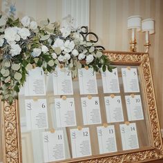 a gold frame with seating cards and flowers on it