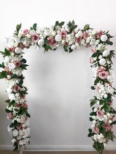 a white and pink floral arch with greenery