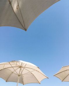 three white umbrellas sitting next to each other under a blue sky