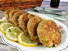 fried crab cakes on a plate with lemons and parsley