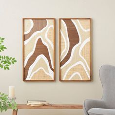 two abstract paintings hang on the wall next to a table with a plant in it