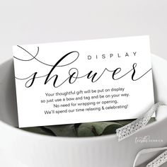 a white bowl filled with flowers next to a card that says display shower on it