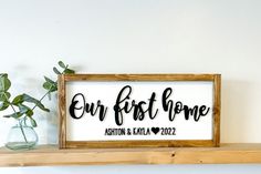 a wooden sign that says our first home on it next to a potted plant