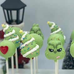 green cake pops with white frosting and sprinkles on them in front of a christmas tree