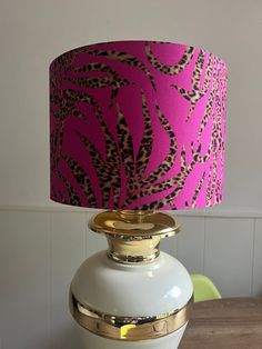 a white table with a pink and gold lamp on it