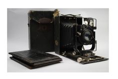 an old fashioned camera sitting on top of a table next to a notebook and folder